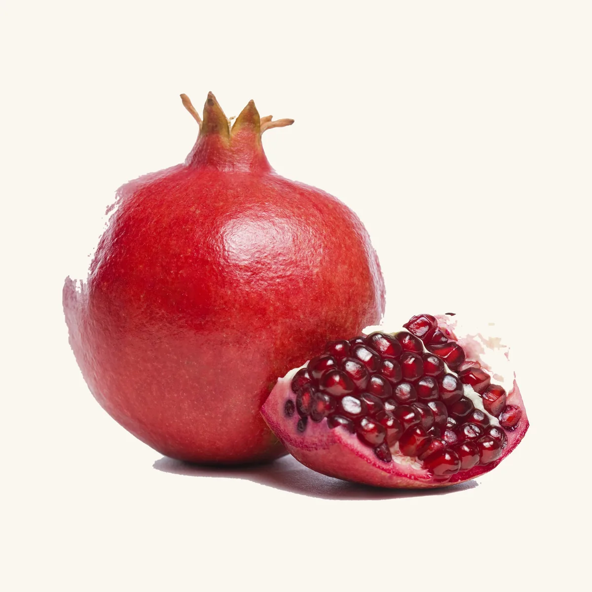 A whole pomegranate beside a halved pomegranate showing the seeds